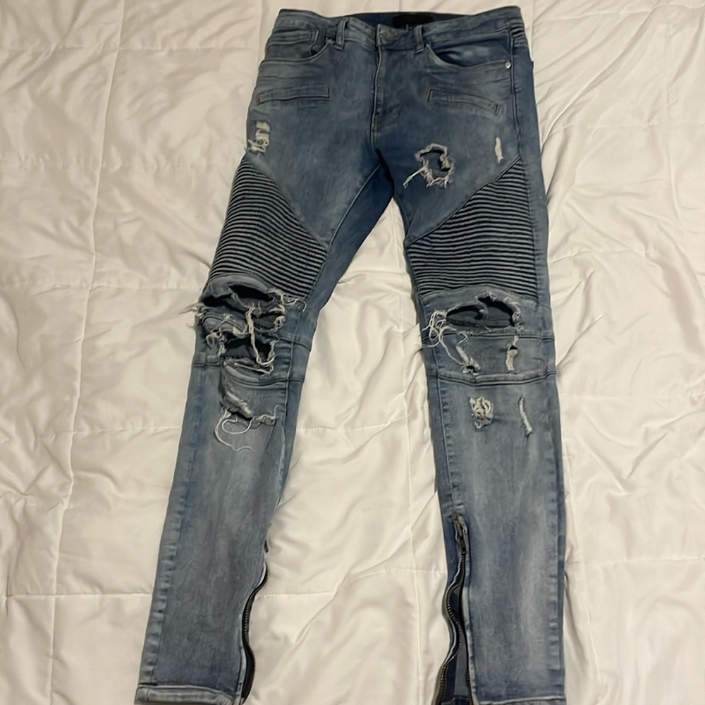 Ripped and distressed blue jeans with ribbed pleats